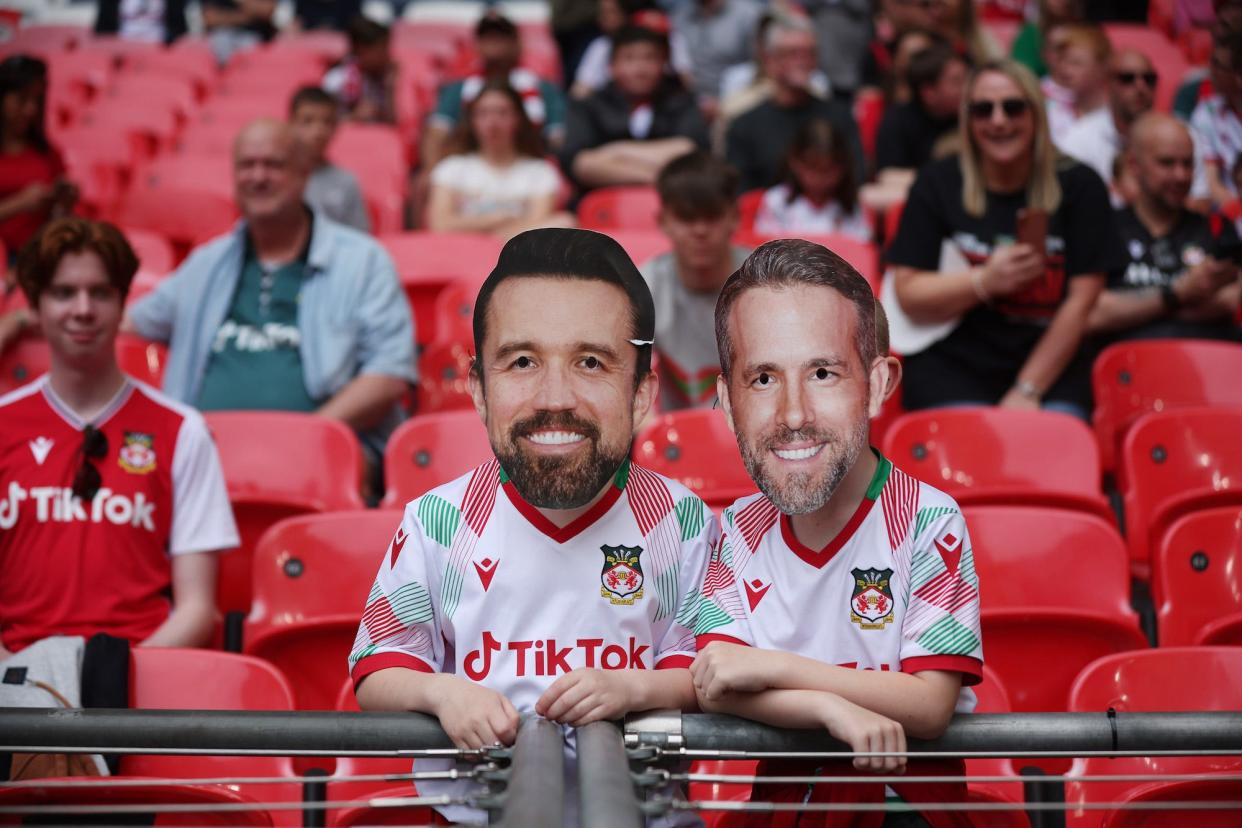 A Wrexham fan with novelty masks showing Wrexham Owners Rob McElhenney (L), and Ryan Reynolds (r), with a home made top hat inside Wembley Stadium during the Buildbase FA Trophy Final between Bromley and Wrexham at Wembley Stadium