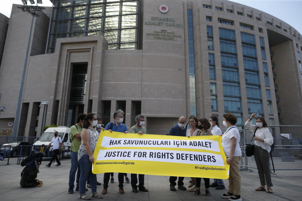 Protesters from Amnesty International stage a protest outside a court in Istanbul, Friday, July 3, 2020, where the trial of 11 prominent human rights activists for terror-related charges and adjourned proceedings was continuing. The banner reads in Turkish: 'Justice for Rights Defenders'. The closely-watched case against Amnesty International's former Turkey chairman and 10 other activists heightened concerns about Turkey's treatment of human rights defenders and helped sour Turkey's relations with European nations, notably with Germany. (AP Photo/Emrah Gurel)