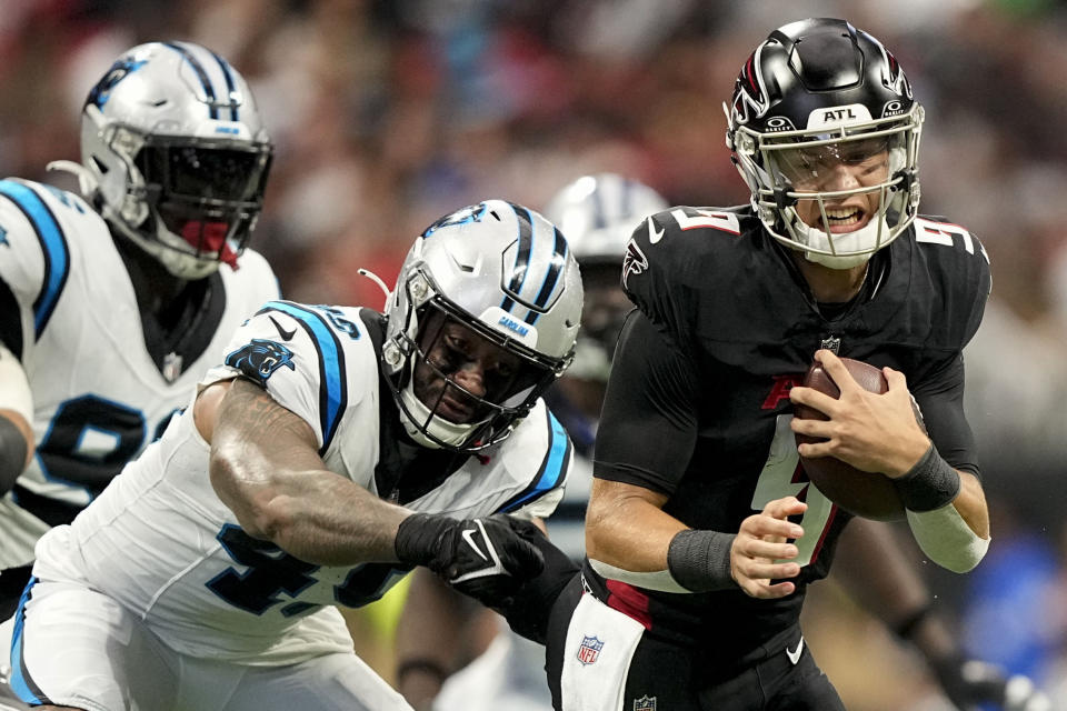 Atlanta Falcons quarterback Desmond Ridder (9) evades a tackle by Carolina Panthers linebacker Frankie Luvu (49) during the first half of an NFL football game, Sunday, Sept. 10, 2023, in Atlanta. (AP Photo/Brynn Anderson)