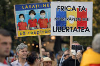 People hold banners that read "Let us breathe" and "Your fear won't take my freedom" during a protest in Bucharest, Romania, Saturday, Sept. 19, 2020. Several hundred Romanians, including many families with young children, held a protest in the country's capital against measures meant to curb the spread of the coronavirus, especially social distancing and the mandatory use of masks in schools. (AP Photo/Vadim Ghirda)