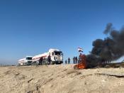 Iraqi demonstrators block the road with burning tires during ongoing anti-government protests in the outskirts of Nassiriya