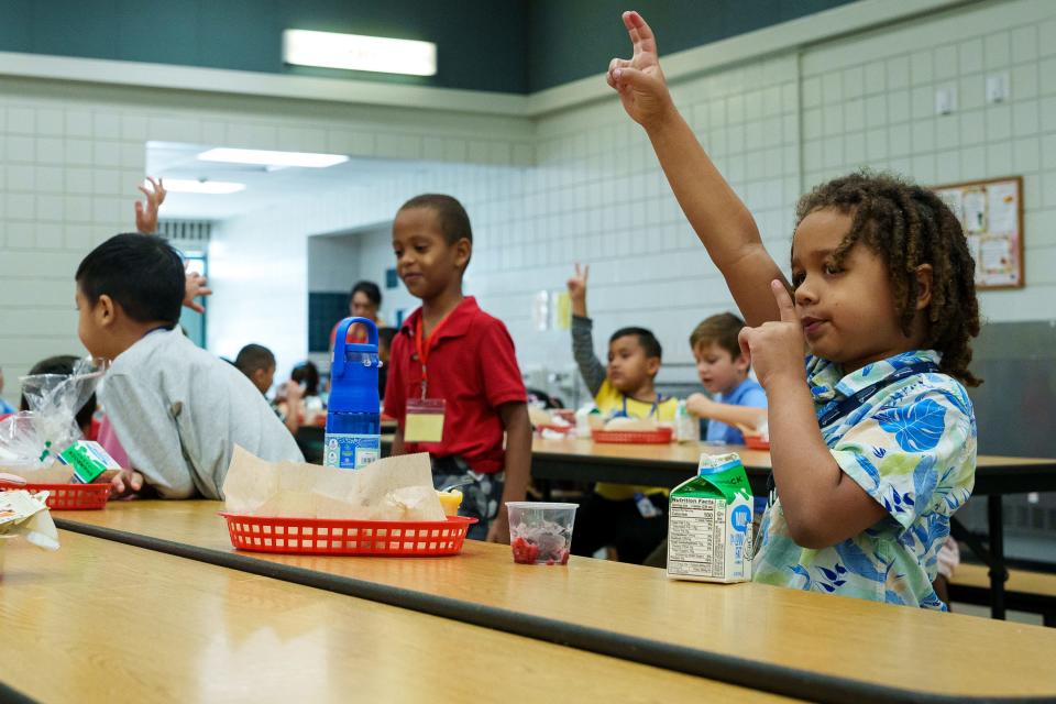 First grader Ezra Farrel raises his hand as the kids quiet down in the Alhambra Traditional School lunch room on August 28, 2023, in Phoenix.