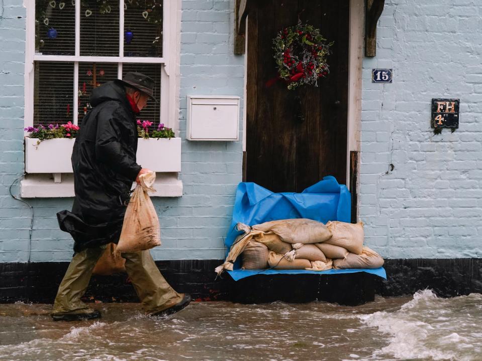 A person places sand bags outside a property in Langstone as Storm Barra hits the UK with disruptive winds, rain and snow (PA)