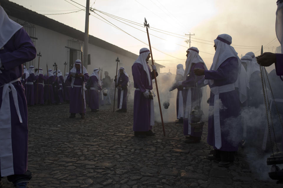 Penitents burn incense as they take part in a procession by La Merced church as part of Holy Week celebrations in Antigua Guatemala, Friday, April 18, 2014. Holy Week commemorates the last week of the earthly life of Jesus Christ culminating in his crucifixion on Good Friday and his resurrection on Easter Sunday. (AP Photo/Moises Castillo)