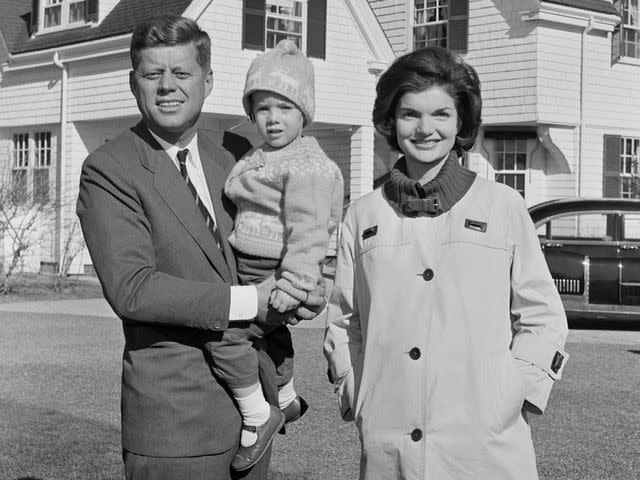 <p>Bettmann/Getty</p> President John F. Kennedy holds his daughter Caroline alongside Jackie Kennedy.