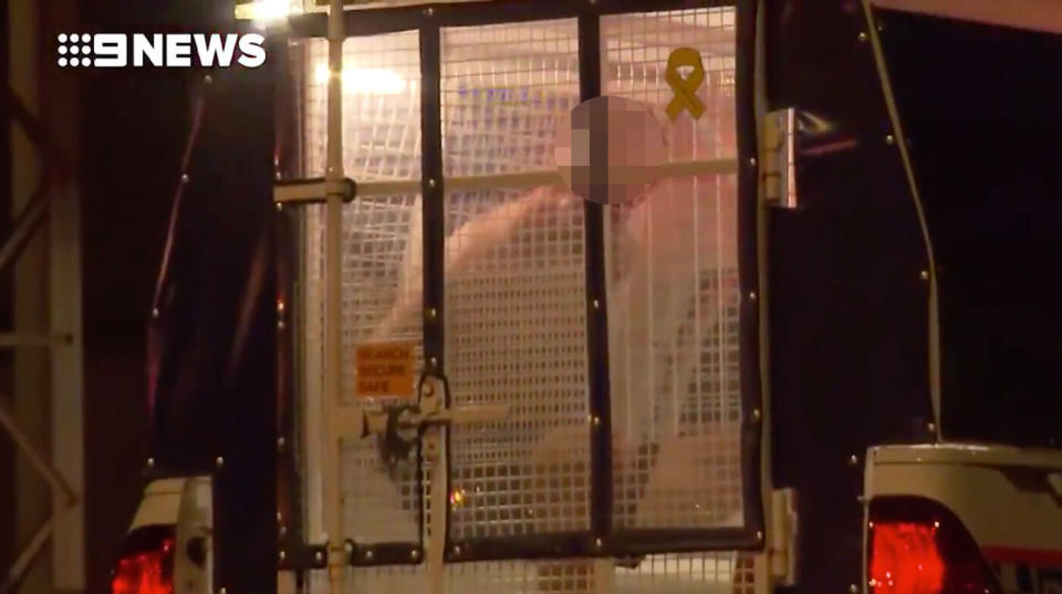 A man is pictured in the back of a police wagon following a shooting in Darwin. 