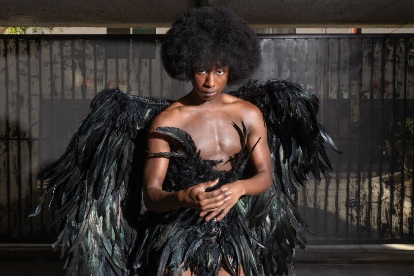 Tyris Winter standing in a parking garage wearing a black feather raven costume.