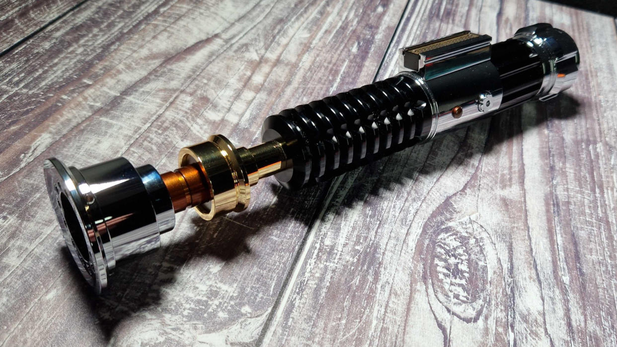  The hilt of the SabersPro Obi Wan EP3 on a wooden surface 