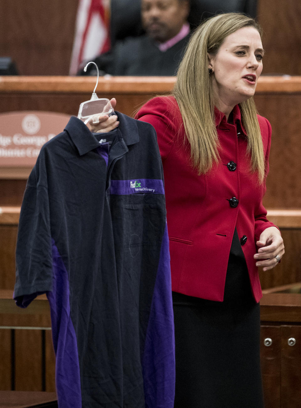 Prosecutor Samantha Knecht holds up a FedEx shirt, which was entered as evidence earlier in the trial, during closing arguments in Ronald Haskell's capital murder trial, Wednesday, Sept. 25, 2019, in Houston. Haskell is on trial for the 2014 shooting of six members of his ex-wife's family in suburban Houston. (Brett Coomer/Houston Chronicle via AP)