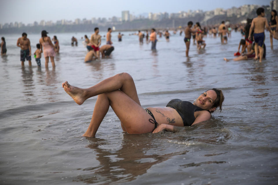 In this Feb. 16, 2020 photo, transgender Natalia, a Venezuelan migrant, strikes a pose as she wades in shallow waters along the shore of Agua Dulce beach in Lima, Peru. (AP Photo/Rodrigo Abd)