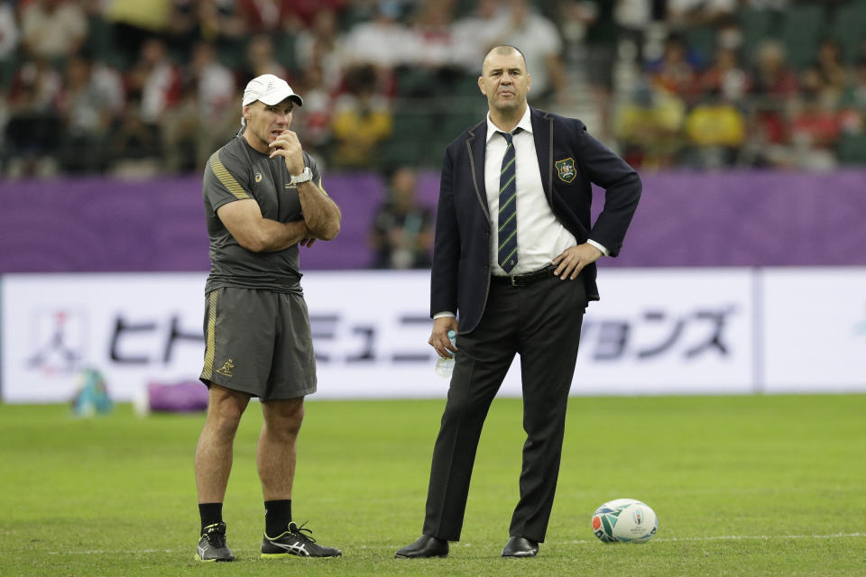 Australia coach Michael Cheika, right, watches as his team warm up before the Rugby World Cup quarterfinal match at Oita Stadium between England and Australia in Oita, Japan, Saturday, Oct. 19, 2019. (AP Photo/Aaron Favila)