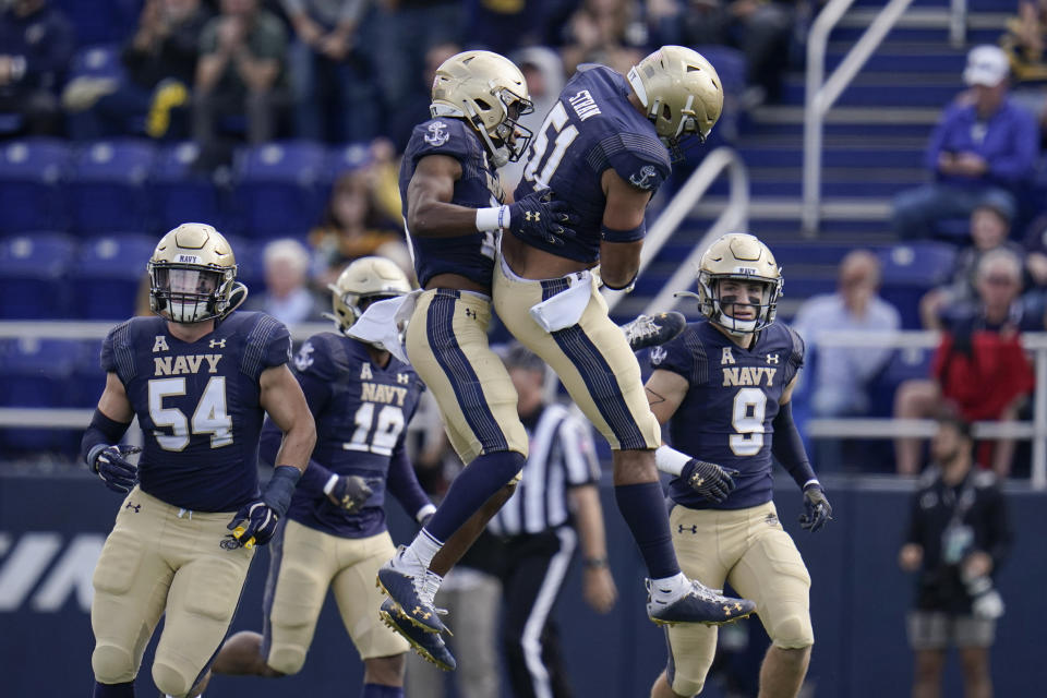 Navy cornerback Jamal Glenn, center left, celebrates with linebacker Nicholas Straw after Glenn intercepted a pass from Cincinnati quarterback Desmond Ridder, not visible, during the first half of an NCAA college football game, Saturday, Oct. 23, 2021, in Annapolis, Md. (AP Photo/Julio Cortez)