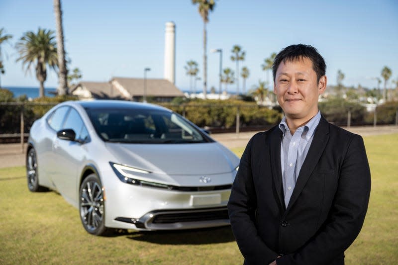 Chief engineer Satoki Oya standing in front of a silver 2023 Toyota Prius.