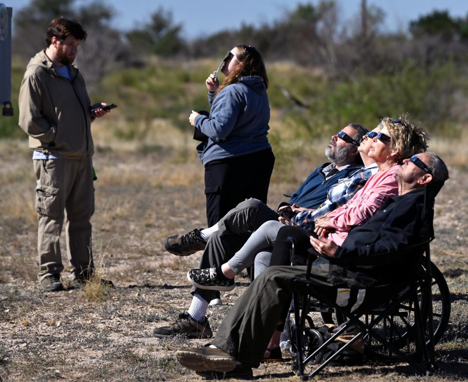 Visitors near the Chaparral Pavilion at San Angelo State Park watch as the moon almost covers the entire sun during Oct. 14's eclipse.