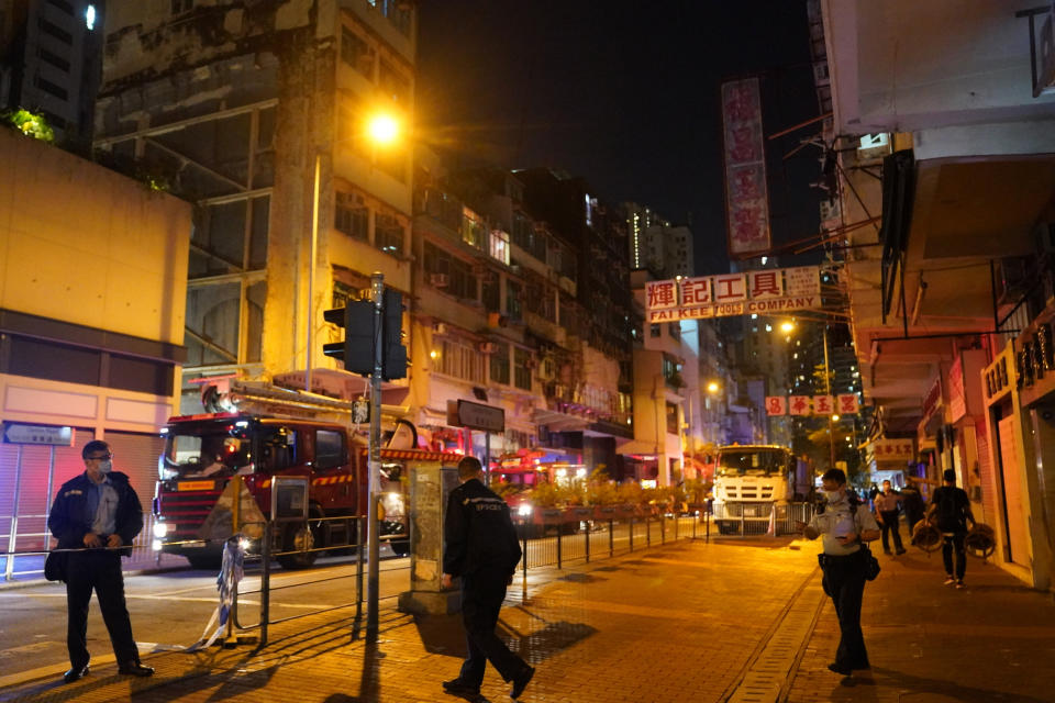 In this photo provided by China's Xinhua News Agency, fire fighters and police officers investigate a fire scene in Hong Kong, Sunday, Nov. 15, 2020. City authorities said a fire in a crowded residential district in Hong Kong has “caused a number of deaths and injuries”. (Lui Siu Wai/Xinhua News Agency via AP)