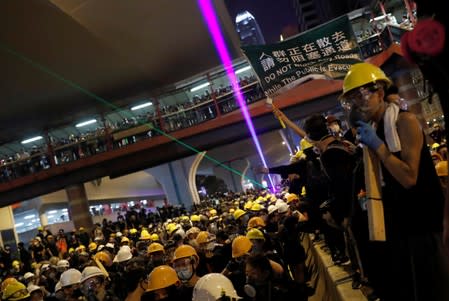 Anti-extradition bill demonstrators stay on barriers as they face riot police, after a march to call for democratic reforms, in Hong Kong