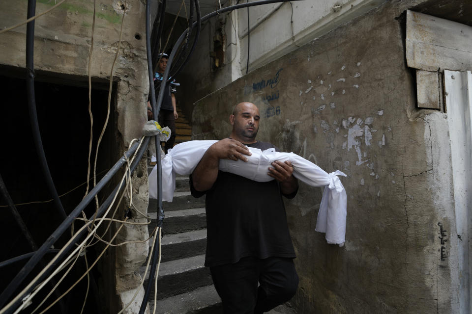 FILE - A man carries the body of a young girl from the family house before the funeral procession for seven people killed when a boat packed with migrants sunk over the weekend as the Lebanese navy tried to force it back to shore, in Tripoli, north Lebanon, Monday, April 25, 2022. A week ago, a boat carrying around 60 Lebanese trying to escape their country and reach Europe sank in the Mediterranean after colliding with a Navy ship. At least seven people are known dead and at least six are missing. The tragedy underscored the desperation among many Lebanese after the collapse of their country's economy. (AP Photo/Hassan Ammar, File)
