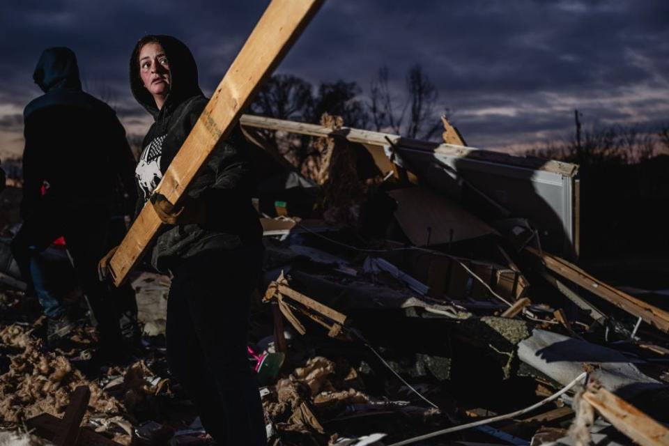 A resident of Clarksville, Tennessee, lifts a board to add to a pile in search of pets and belongings of a destroyed home in the aftermath of a tornado on Dec. 10, 2023.