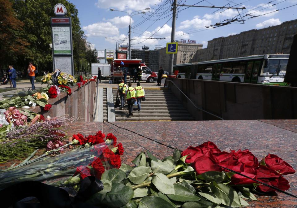 Flowers are left in memory of victims of Tuesday's accident, in which three carriages derailed on a train during morning rush hour, at the entrance to a metro station in Moscow July 16, 2014. Russian state investigators said on Wednesday they had detained two Moscow metro workers suspected of safety breaches that may have caused an accident that killed at least 21 people. (REUTERS/Sergei Karpukhin)