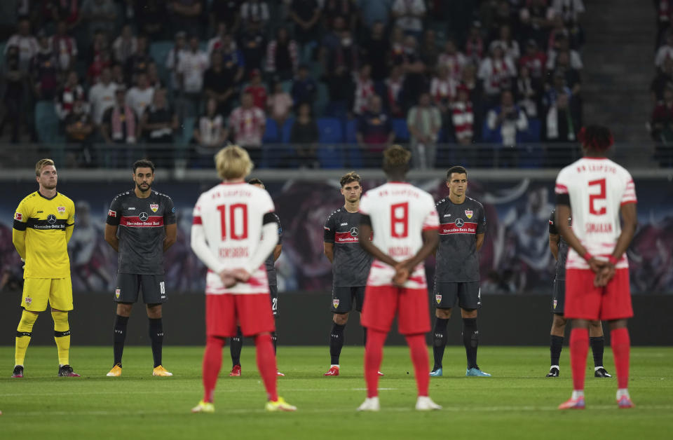 Players stand for a minute of silence prior to the German Bundesliga soccer match between RB Leipzig and VfB Stuttgart in Leipzig, Germany, Friday, Aug. 20, 2021. (AP Photo/Michael Sohn)