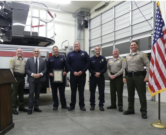 In plain clothes, San Bernardino County Sheriff&#x002019;s Sgt. Jerrod Burns, along with sheriff&#x002019;s officials, stands with some of the paramedics of the Apple Valley Fire Protection District who helped save his life.