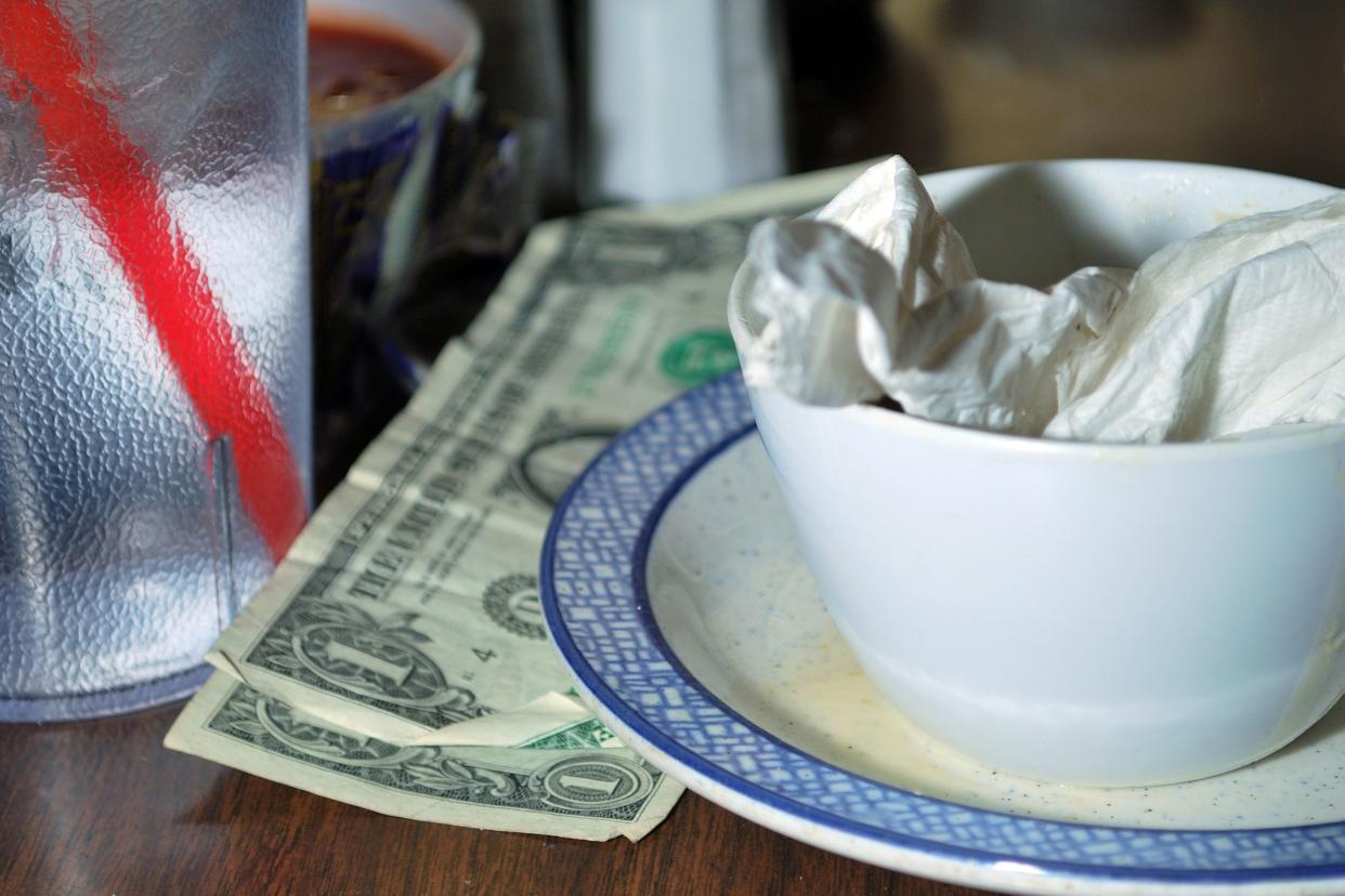 Dollar bills next to dirty dishes on restaurant table