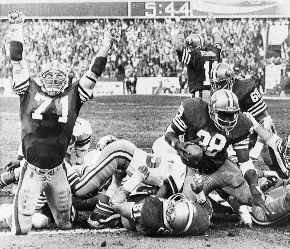 FILE - San Francisco 49ers' Keith Fahnhorst (71) and Joe Montana, rear, signal a touchdown as teammate Johnny Davis scores against the Dallas Cowboys during the NFC title game at Candlestick Park in San Francisco, Jan. 10, 1982. The 49ers-Cowboys playoff history is a rich one from back-to-back conference title games in the early 1970s, the iconic “Catch” in the 1981 season and then the heated rivalry in the 1990s when the Cowboys won the first two meetings on the way to Super Bowl titles and then the Niners took the third game. (AP Photo/File)