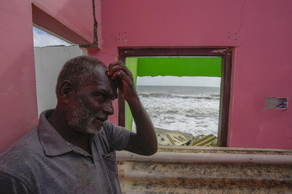 Ranjith Sunimal Fernando gestures as he looks for salvageable items at his home destroyed by erosion in Iranawila, Sri Lanka, Thursday, June 15, 2023. He salvaged what he could from the wreck of what was once his home — wooden support beams, sections of roof and other building materials — to build another further inland. (AP Photo/Eranga Jayawardena)