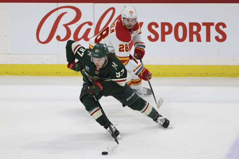 Minnesota Wild left wing Kirill Kaprizov (97) handles the puck against Calgary Flames center Elias Lindholm (28) during the third period of an NHL hockey game Tuesday, March 7, 2023, in St. Paul, Minn. Calgary won 1-0 in a shootout. (AP Photo/Stacy Bengs)