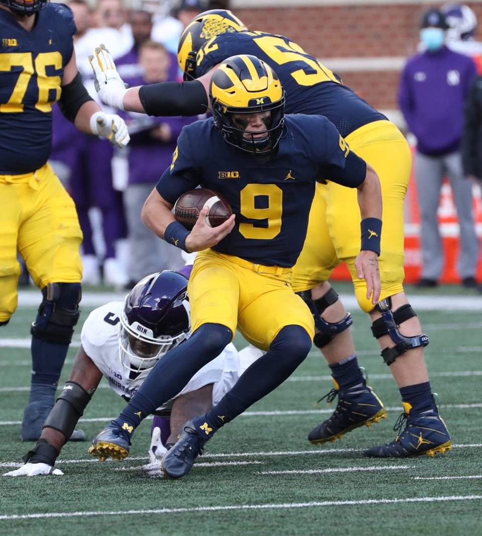 Michigan Wolverines quarterback J.J. McCarthy (9) runs by Northwestern Wildcats defensive lineman Jeffery Pooler Jr. (5) during second half action Saturday, Oct. 23, 2021 at Michigan Stadium.