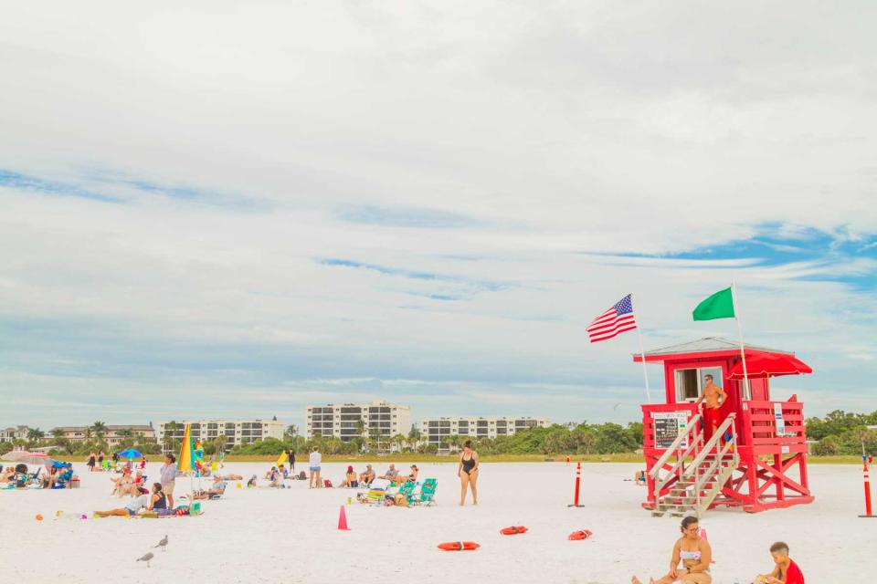 People enjoying Siesta Beach in Sarasota, Florida next to a red lifeguard station