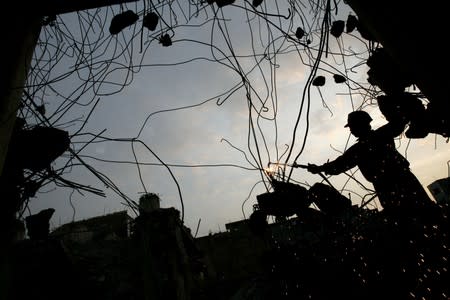 A general view show the silhouette of a labourer welding steel at a demolished construction site in Sanya