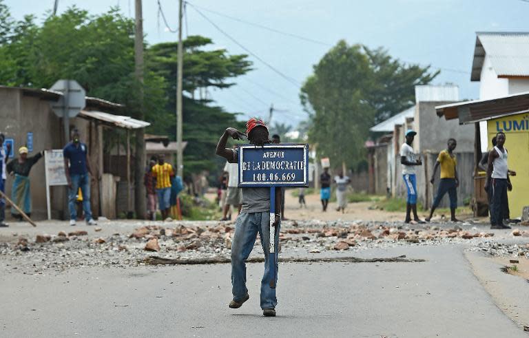 A protestor opposed to Burundian President Pierre Nkurunziza's third term holds a road sign reading 'Avenue of Democracy ' during a demonstration in Bujumbura on May 26, 2015