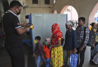 Indian passengers are screened for body temperature as a precautionary measure against COVID-19 at Secunderabad Railway Station in Hyderabad, India, Saturday, March 21, 2020. For most people, the new coronavirus causes only mild or moderate symptoms. For some it can cause more severe illness. (AP Photo/Mahesh Kumar A.)