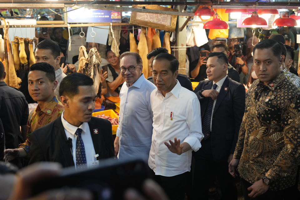 Indonesian President Joko Widodo, center, walks with Malaysian Prime Minister Anwar Ibrahim as they visit a local wet market in Kuala Lumpur, Malaysia, Thursday, June 8, 2023. (AP Photo/Vincent Thian)