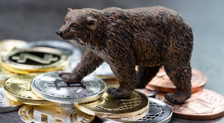cryptos to buy A concept image with a bear figuring standing on top of crypto tokens.