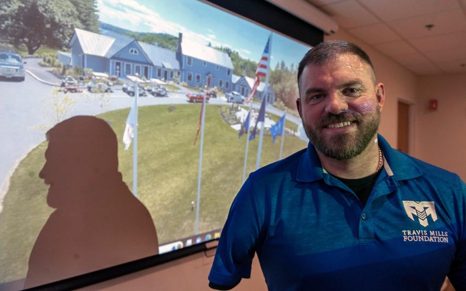 Retired U.S. Army Staff Sgt. and "recalibrated warrior" Travis Mills, of the Travis Mills Foundation, spoke Wednesday night at La Cantina Italiana Restaurant in Framingham. The foundation offers injured combat veterans and their families recreational activities at a relaxing retreat. Behind him is a picture of the Travis Mills Foundation retreat in Mt. Vernon, Maine.