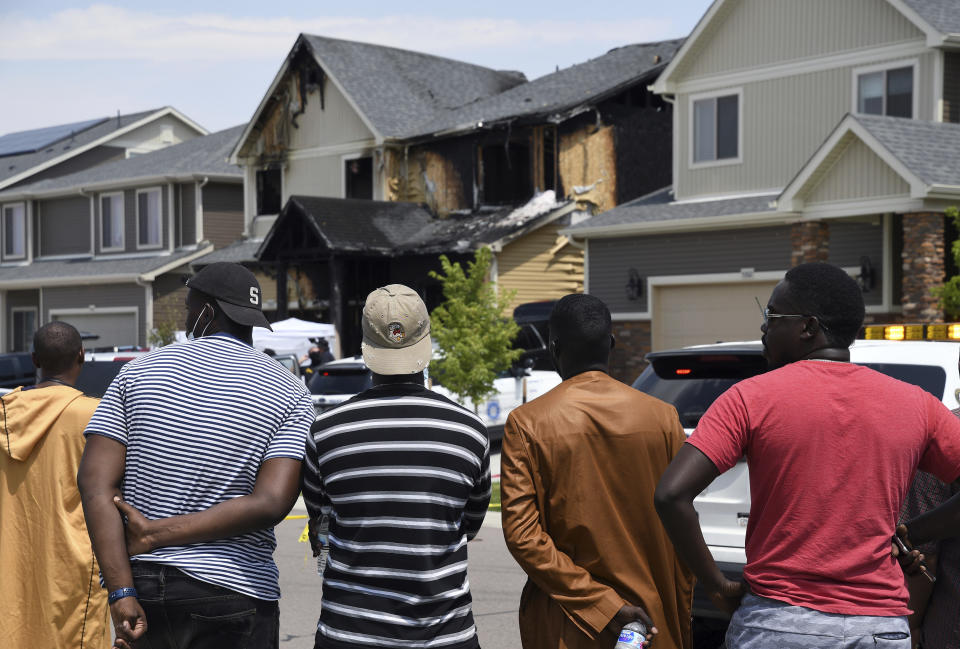 FILE - In this Aug. 5, 2020, file photo, people look at a house where five people were found dead after a fire in Denver. One of three teenagers charged with starting a house fire in Denver that killed five people — apparently out of revenge for a stolen cellphone that was mistakenly traced to the home — was sentenced Friday, March 15, 2024, to 40 years in prison. (AP Photo/Thomas Peipert, File)