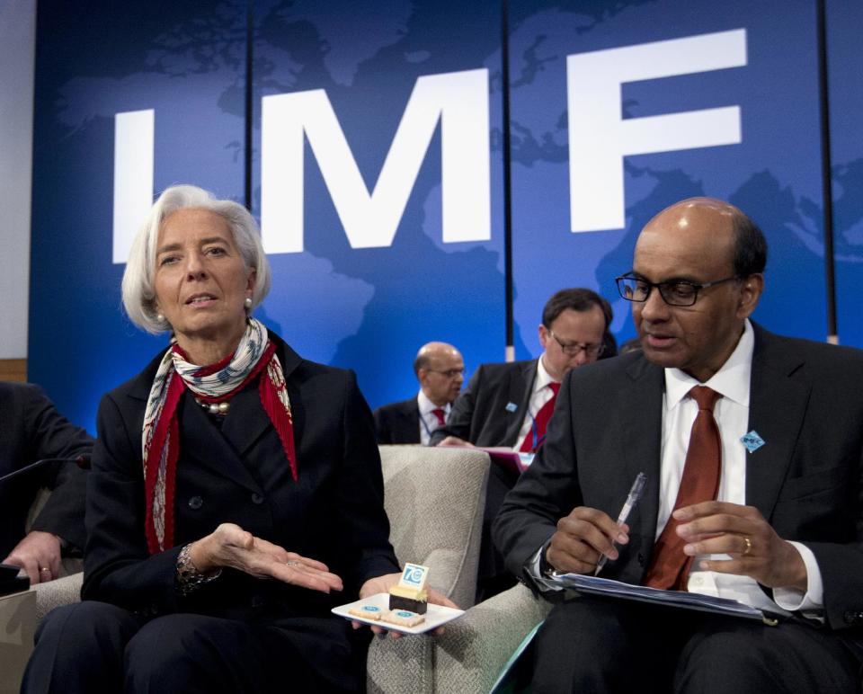 International Monetary Fund (IMF) Managing Director Christine Lagarde show photographers IMF anniversary cookies as IMFC Chair Tharman Shanmugaratnam looks on, Saturday, April 12, 2014, during the International Monetary and Financial Committee (IMFC) meeting at World Bank Group-International Monetary Fund Spring Meetings in Washington. ( AP Photo/Jose Luis Magana)