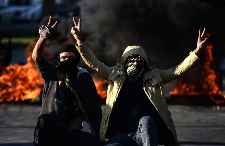 Iraqi demonstrators flash the victory sign next to burning tyres as angry protesters blocked roads in the central shrine city of Najaf, on January 5, 2020, to reject turning the country into an arena for US-Iran conflicts. - Iraq's parliament was expected to vote today on ousting thousands of US troops from military bases, which are threatened by pro-Tehran factions after an American strike killed top Iranian and Iraqi commanders. (Photo by Haidar HAMDANI / AFP) (Photo by HAIDAR HAMDANI/AFP via Getty Images)