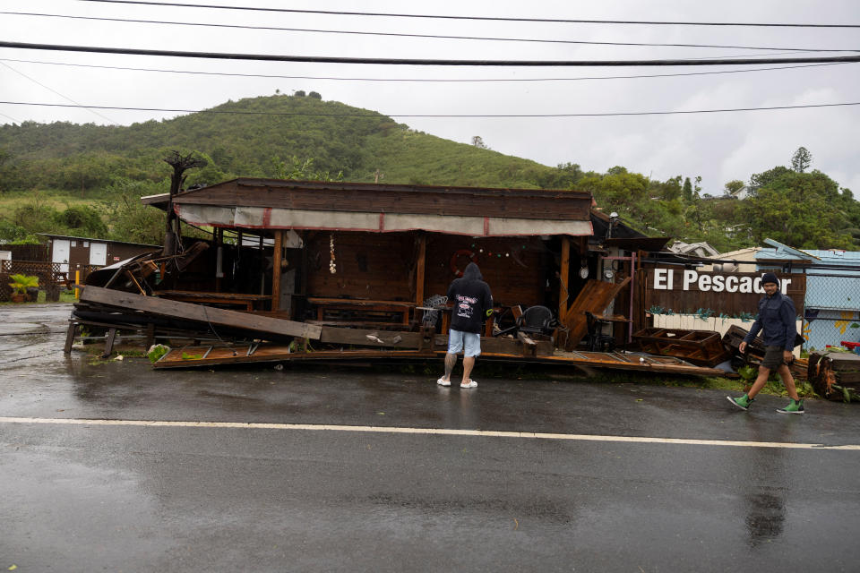 Pessoas examinam os danos a um restaurante após a tempestade tropical Ernesto.