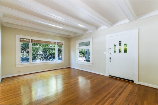 An interior view of the living room with wood floors and ample lighting.