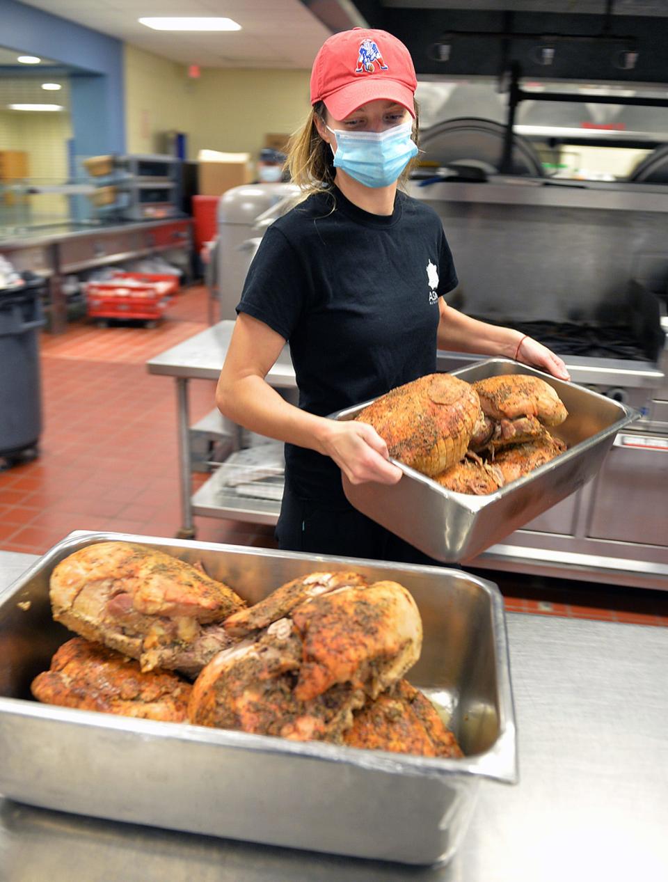 Rachael Boland, operations supervisor at the Assabet Valley Regional Technical High School cafeteria, carries turkeys that will become turkey pies served to students and staff.