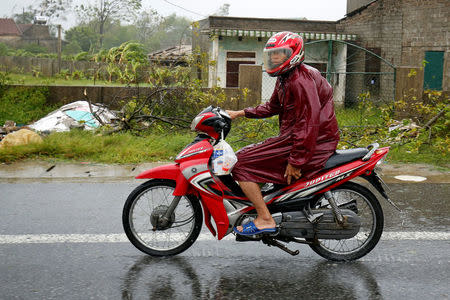 A man rides a motorcycle with his child on the back while he struggles against wind and rain as Doksuri storm hits the land in Ha Tinh province, Vietnam September 15, 2017. REUTERS/Kham