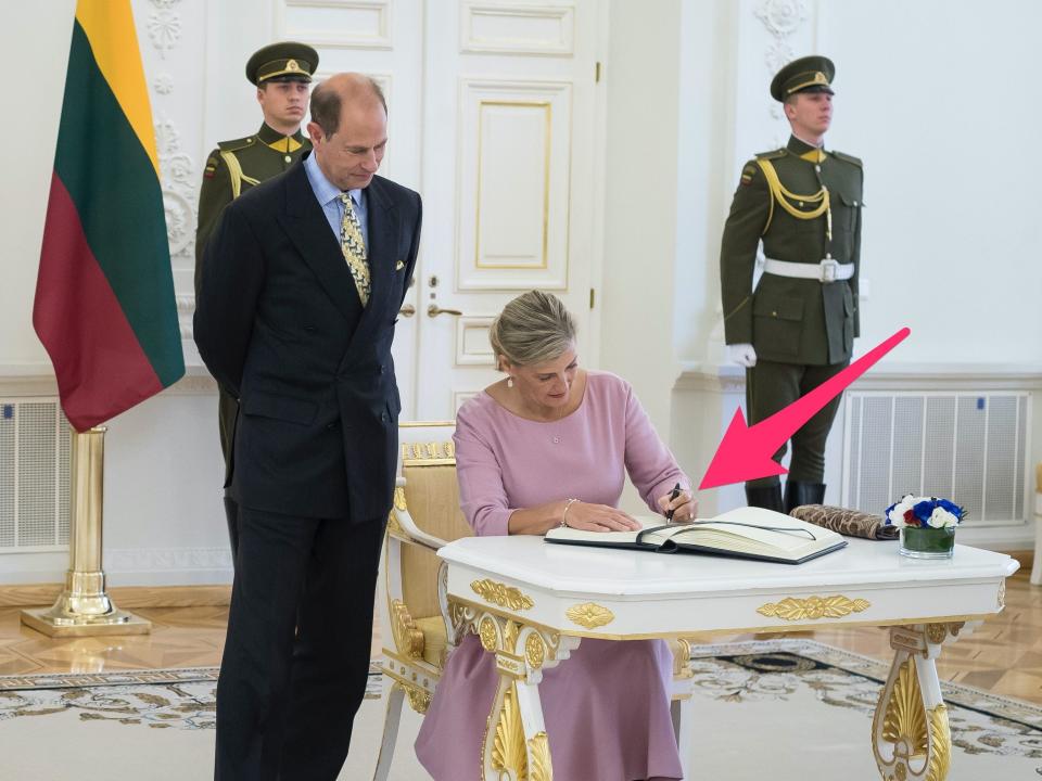 Sophie, Countess of Essex, signs a guest book with her left hand.