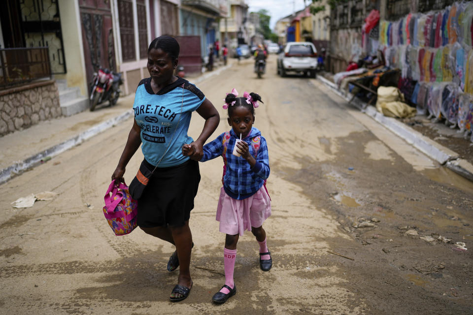 Una niña toma una bebida envasada tras salir de la escuela, en Cap-Haitien, Haití, el 17 de abril de 2024. (AP Foto/Ramón Espinosa)