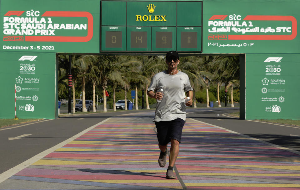 A man runs in front of a Formula One countdown clock on the corniche walkway in Jiddah, Saudi Arabia, Sunday, Nov. 21, 2021. The Formula One race takes place from Dec. 3-5 along the Red Sea city of Jiddah's coast, marking the first time the premier sporting event is held in Saudi Arabia. (AP Photo/Amr Nabil)