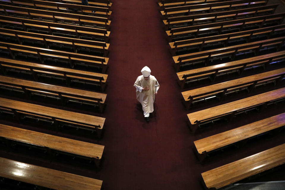 Bishop William Joensen proceeds down the main aisle at the conclusion of Holy Thursday Mass in a near empty St. Ambrose Cathedral, Thursday, April 9, 2020, in Des Moines, Iowa. COVID-19 causes mild or moderate symptoms for most people, but for some, especially older adults and people with existing health problems, it can cause more severe illness or death. (AP Photo/Charlie Neibergall)