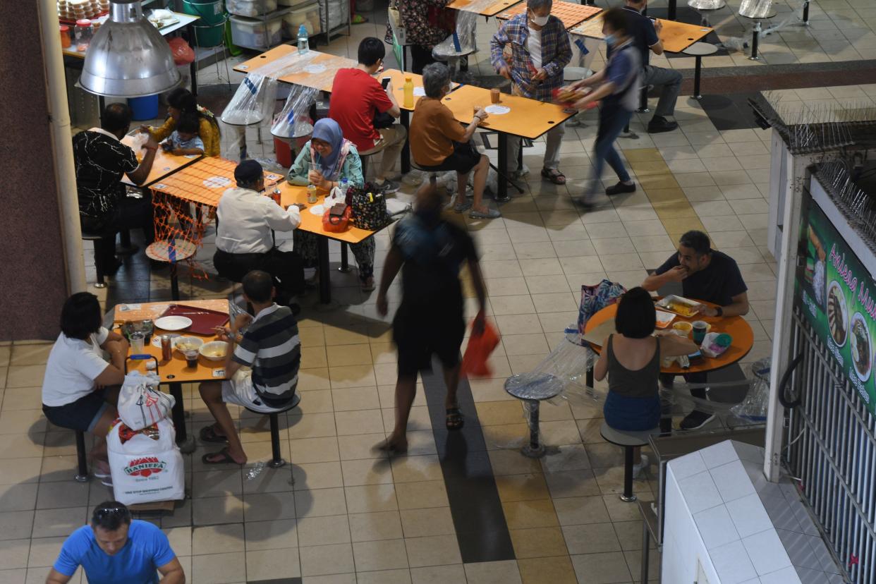 People, in groups of two, dine in Singapore's Tekka Food Center on July 8, 2021.  From July 12, Singapore will begin to implement updated measures, which include allowing groups of up to five persons to dine-in at food and beverage establishments. (Photo by Then Chih Wey/Xinhua via Getty Images)