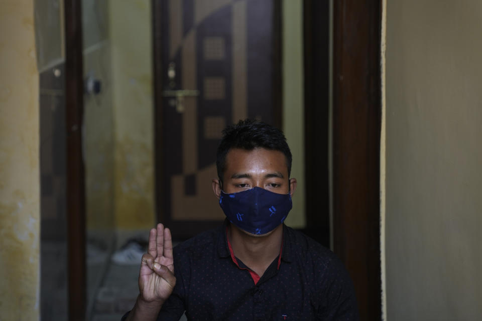 A Myanmar public servant refugee, 26, who fled during the violence in the town of Thantlang in Chin state, northwestern Myanmar, salutes with the common three-finger symbol of resistance at an undisclosed location, in India, Monday, Dec. 13, 2021. (AP Photo/Manish Swarup)